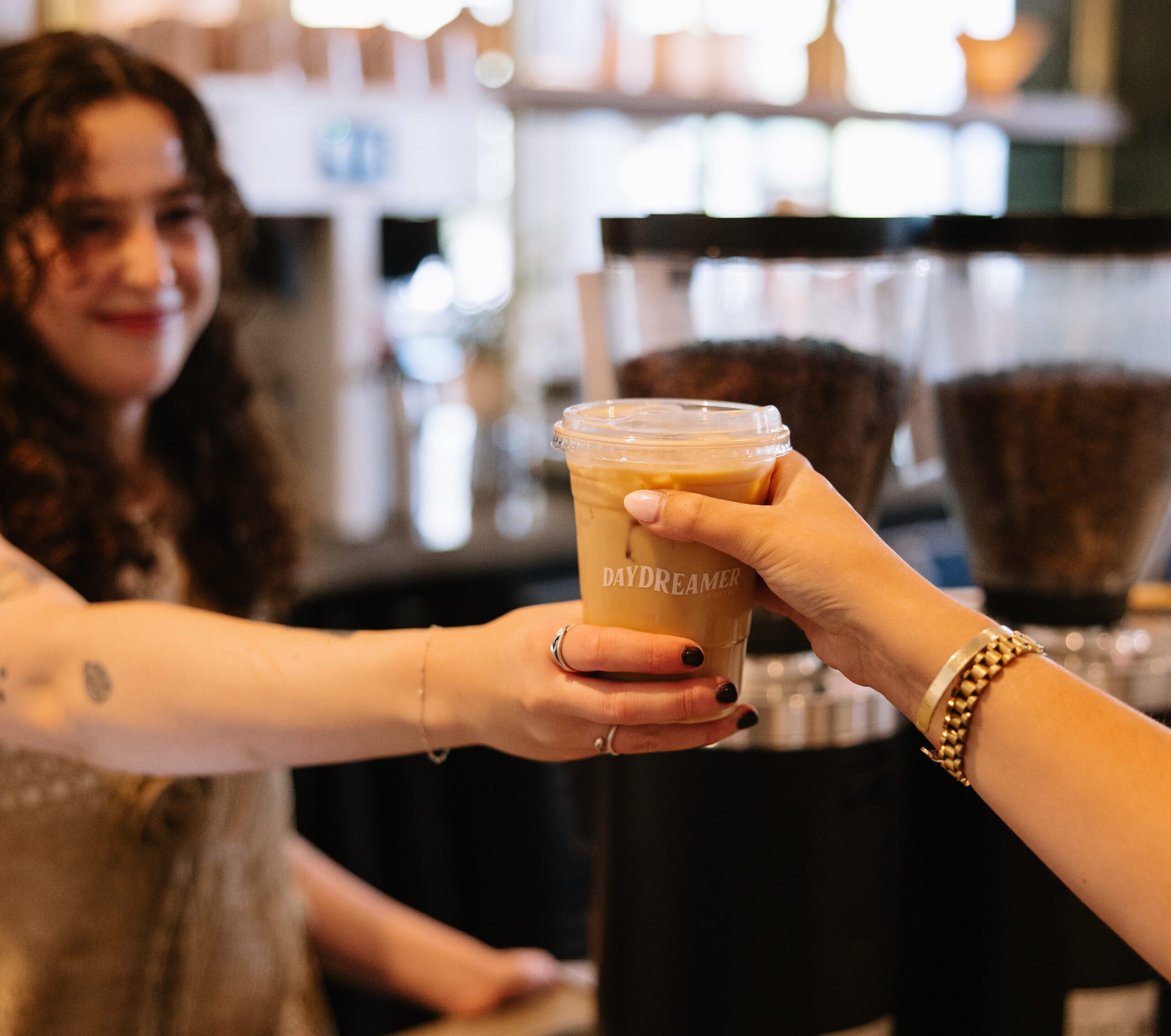 Rambler Tempe Barista at Daydreamer handing a student an Iced latte