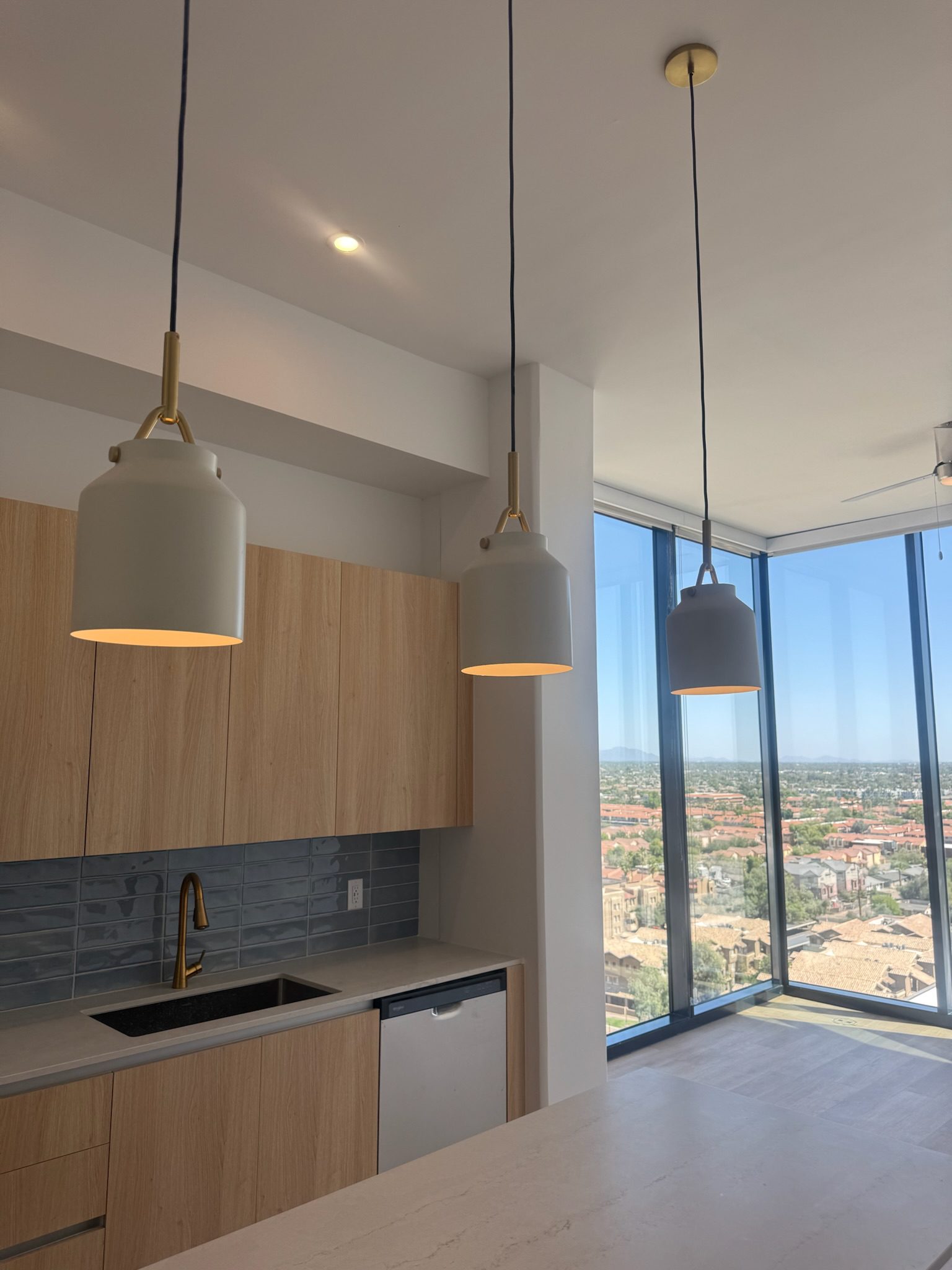 A completed unit interior showing the kitchen, pendants and floor to ceiling windows.