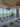 A modern yoga studio with floor-to-ceiling windows, offering a view of a city and distant mountains. Yoga mats, blocks, and towels are neatly arranged on the floor, and there are plants and stylish ceiling lights.
